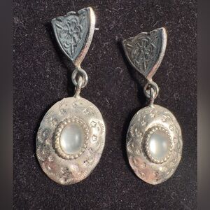 Vintage-style silver tone dangle earrings, oval-shaped, textured medallion drop.